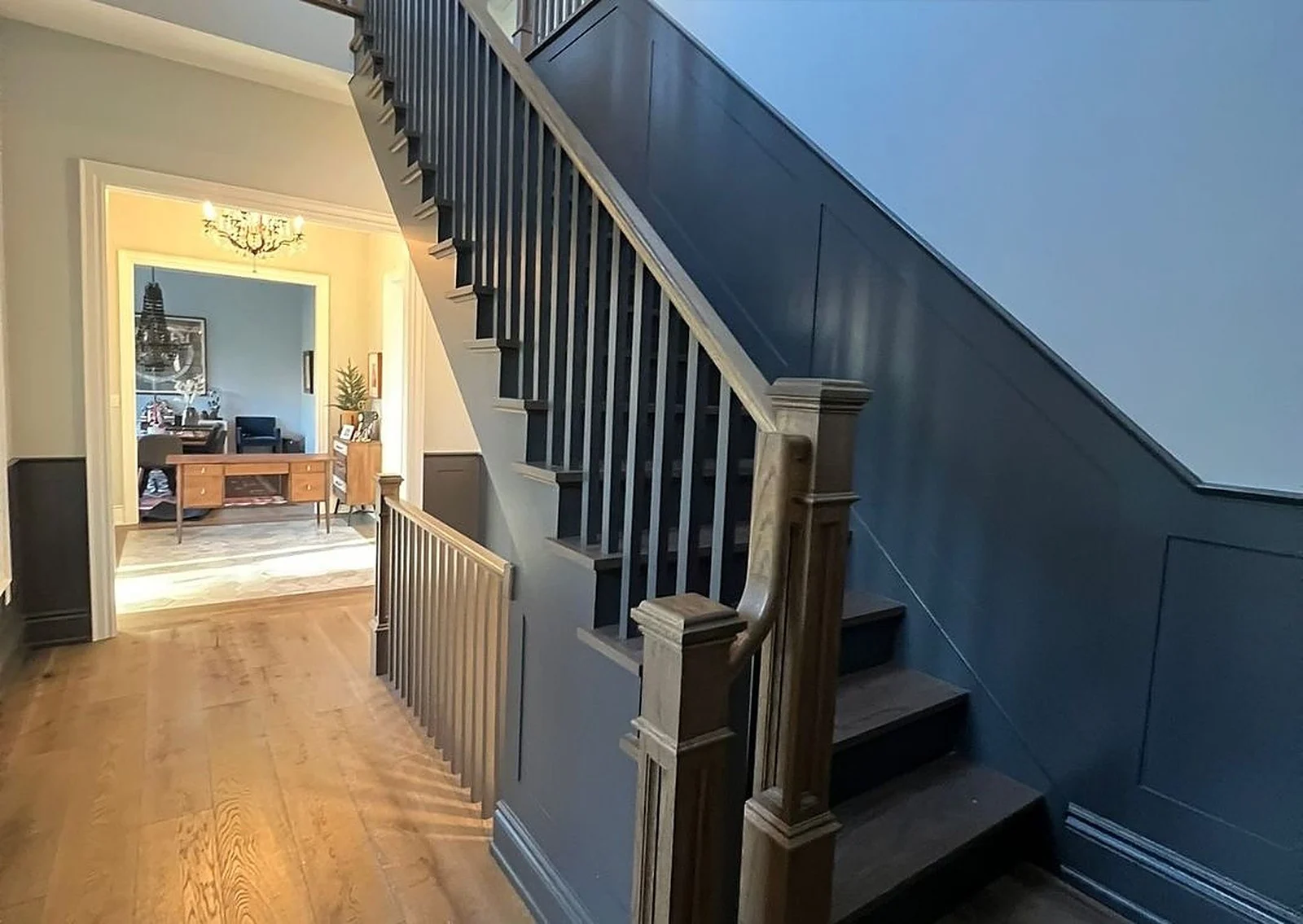 Foyer staircase with navy wainscoting and dark treads