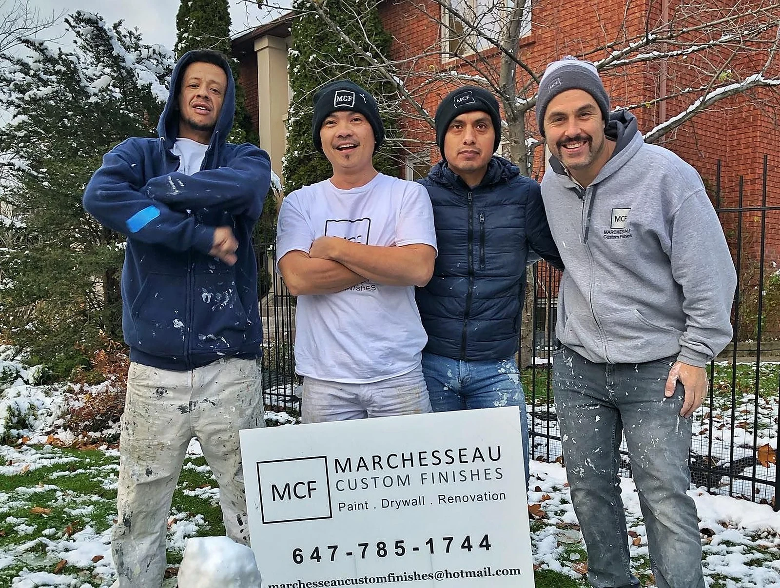 Paul and three crew members outside a job site in winter, beside a Marchesseau lawn sign
