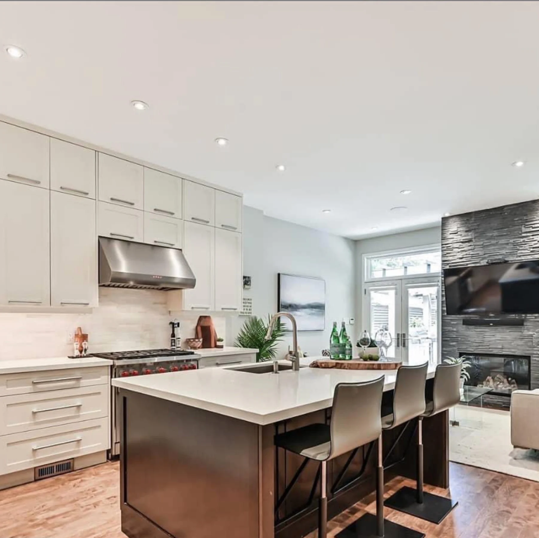 Bright white kitchen with a dark island and a stone fireplace wall