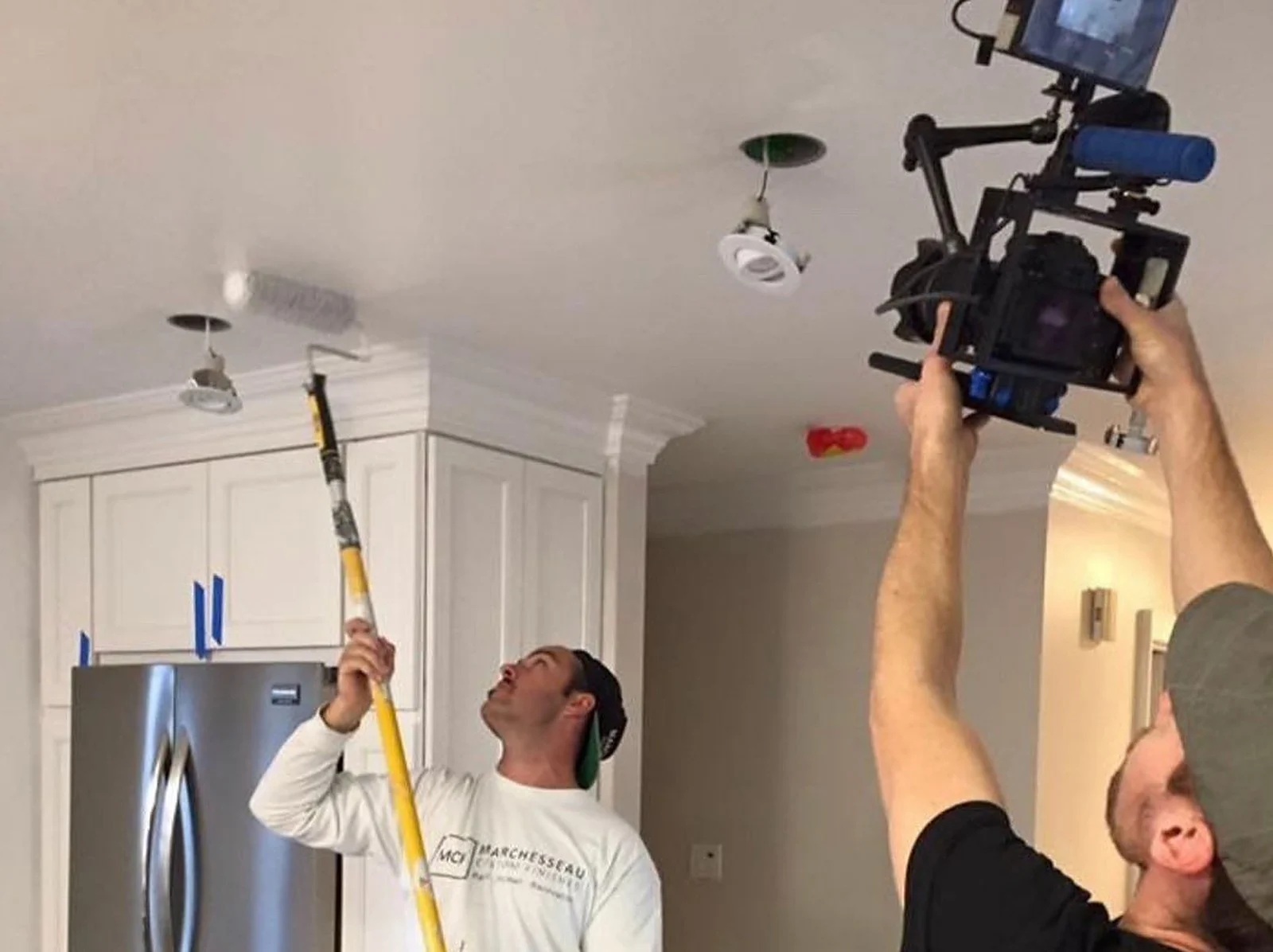 Paul painting a ceiling while a TV crew films