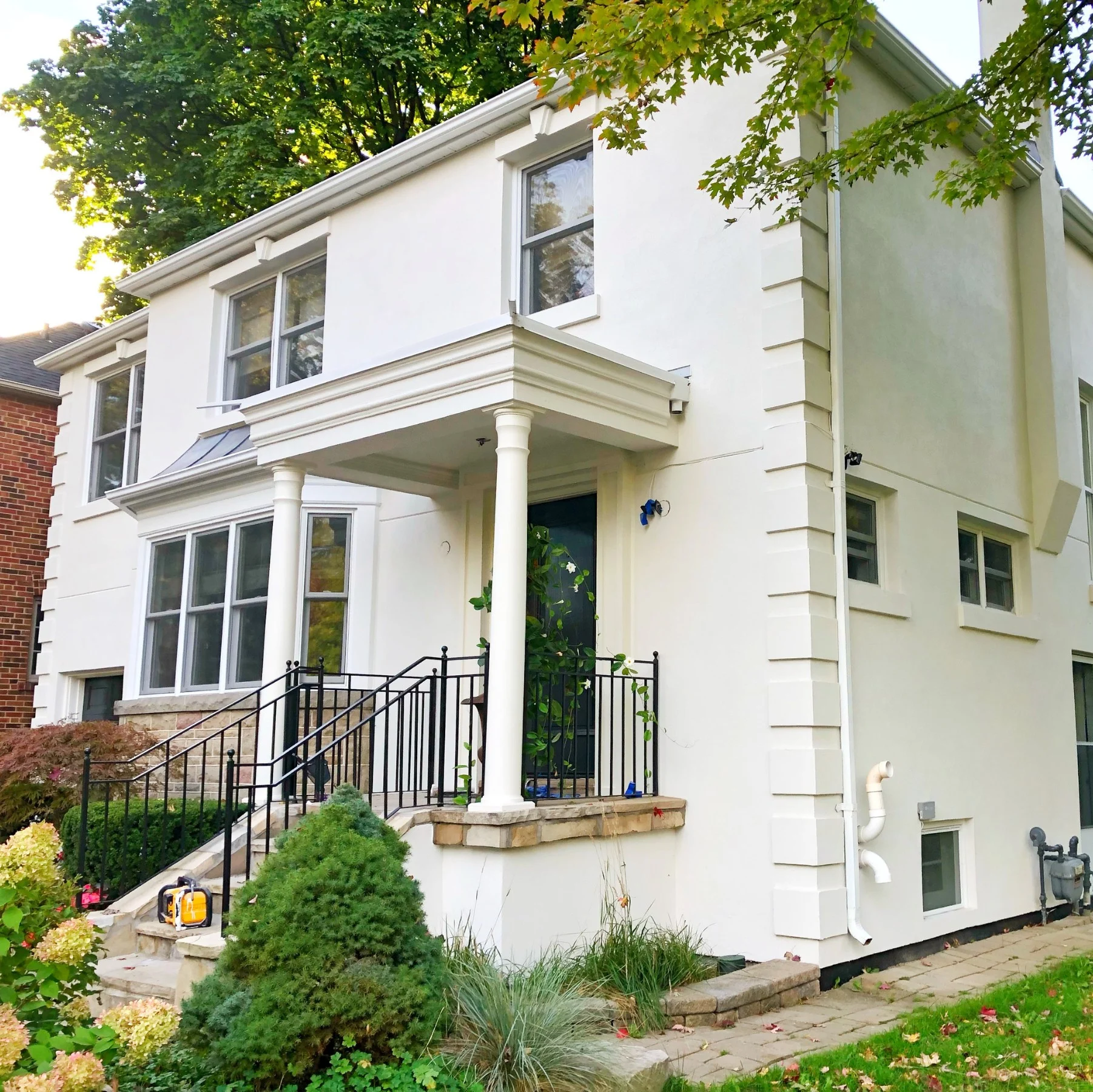 White two-storey house with columns and black railings, freshly painted